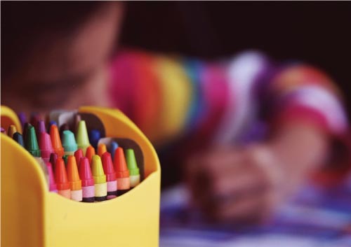 Décoration anniversaire enfant - Enfant qui dessine et pot à crayon de couleur posez devant lui